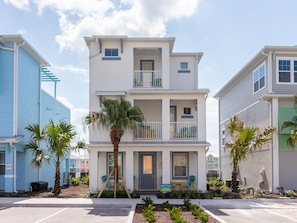 Stylish two-story building with a central entrance and two upper-floor balconies, set amidst a serene landscaped area with palm trees and shrubs.