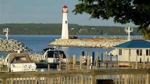 Un phare, un quai avec des bateaux et un petit bâtiment doté d’un toit bleu.