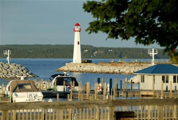 A lighthouse, a dock with boats, and a small building with a blue roof.