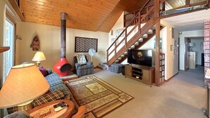 A cozy living room with a fireplace, a staircase, a television, and a comfortable seating area. - The House that Jack Built (Moran)