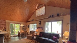 A cozy living room with a sofa, a dining table, and a kitchen area. - The House that Jack Built (Moran)