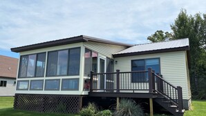 A two-story house with a deck, large windows, and a small garden.