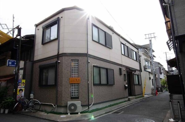 A two-story residential building with a brick facade, large windows, and a visible air conditioning unit. - Koueki (Kyoto)