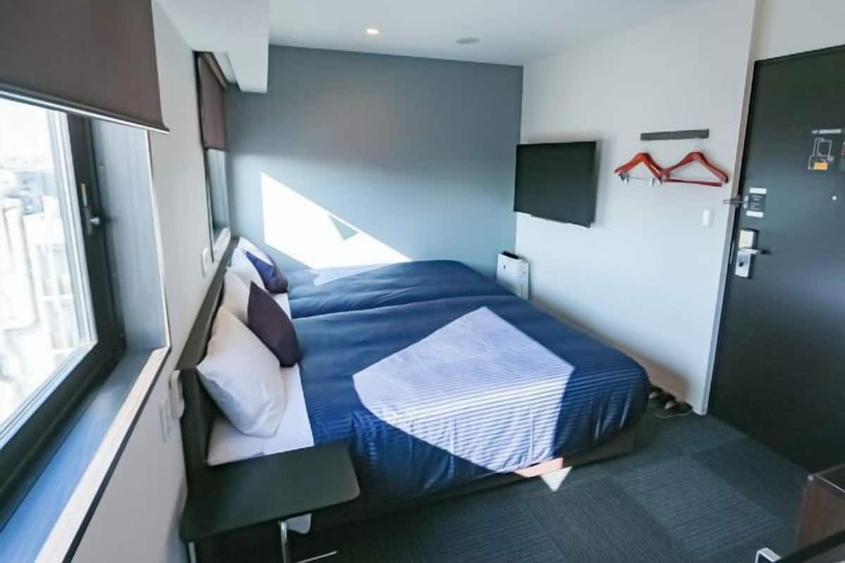 Ein modernes Hotelzimmer mit Bett, Schreibtisch, Fernseher und einer Tür.