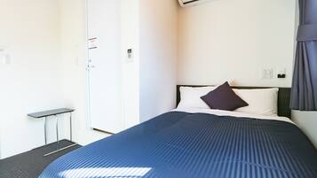 Una habitación de hotel con cama, escritorio y unidad de aire acondicionado en la pared.