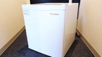 A white Hisense refrigerator in a hallway with carpeted flooring.