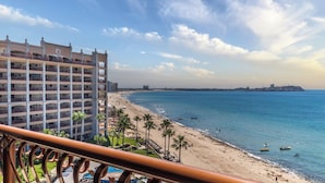 Ein Strandhotel mit mehreren Balkonen, einem Sandstrand und freiem Blick auf das Meer.