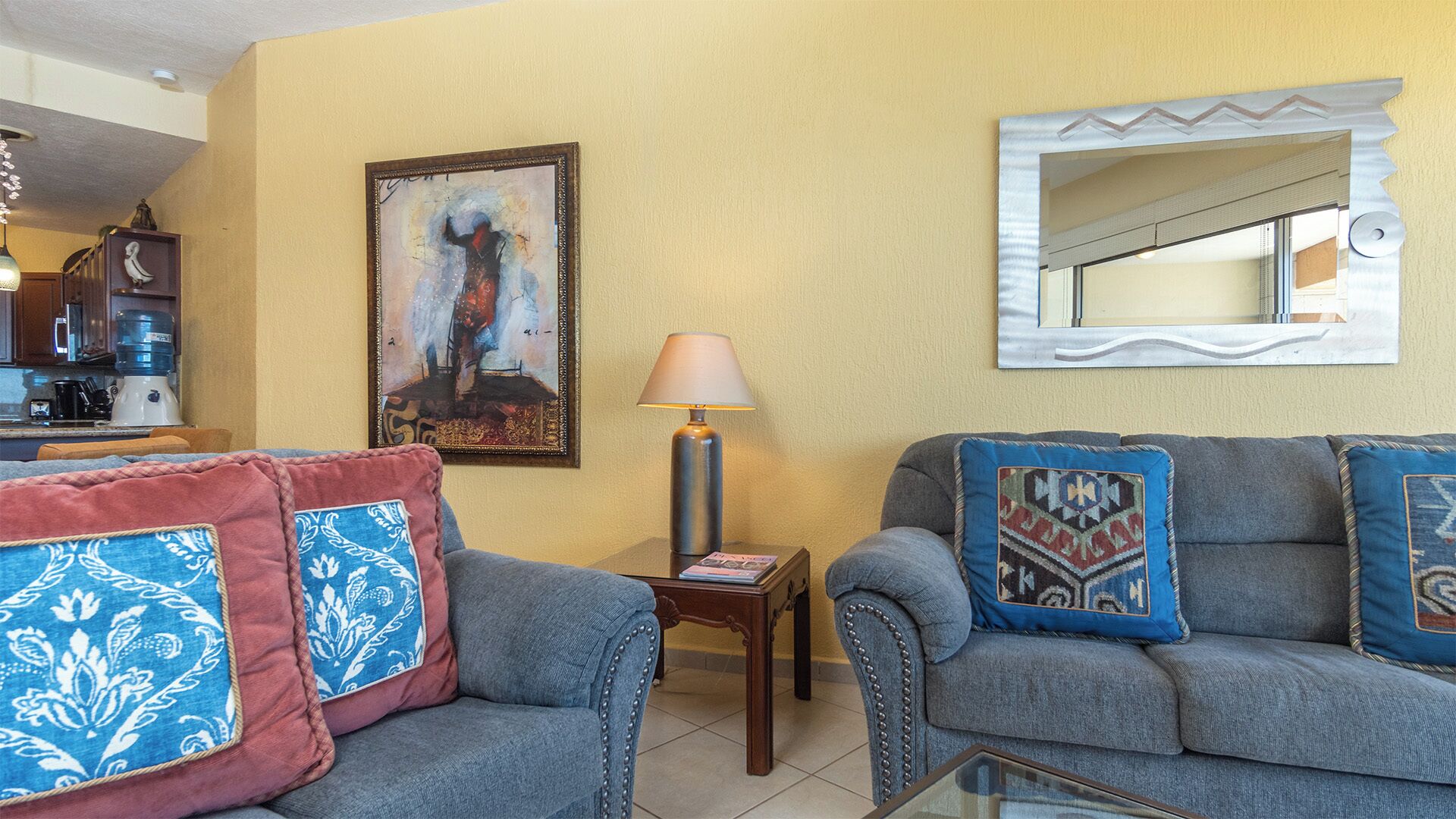 A living room with two sofas, a table, a lamp, and a framed painting on the wall.