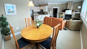 A dining area with a round wooden table and chairs, a small potted plant, and a hanging light fixture.