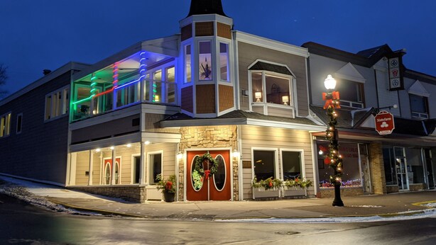 A two-story building with a large front door, multiple windows, and a balcony with colorful lights.