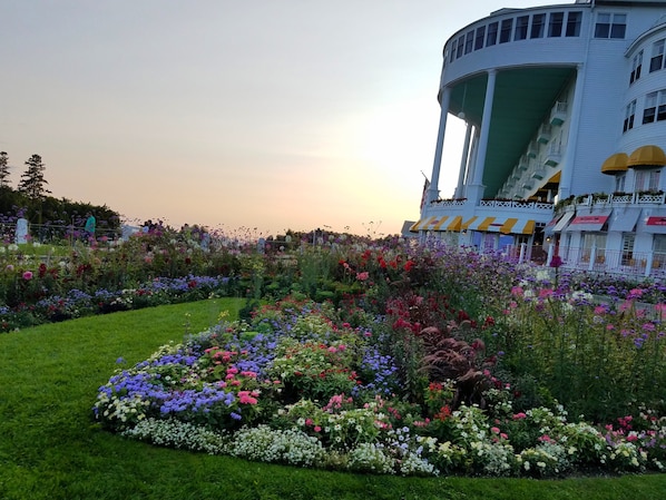 A hotel with a large water tower, surrounded by a well-maintained garden with various flowers.