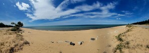 A wide sandy beach with a clear sky and calm sea.