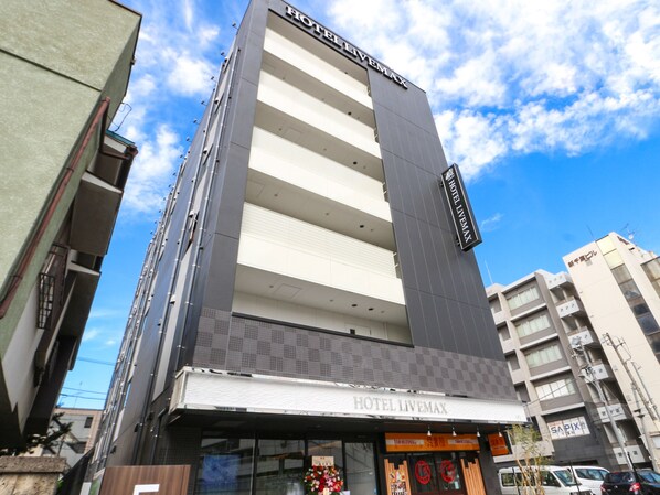 A modern hotel building with a prominent sign reading "HOTEL LIVEMAX".