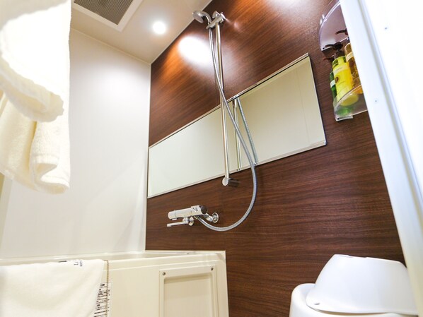 A bathroom with a wooden vanity, a mirror, a showerhead, and a toilet.