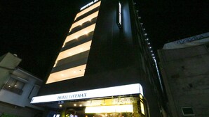 A hotel named HOTEL LIVEMAX with a modern facade and illuminated signage.