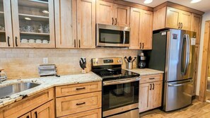 A kitchen with wooden cabinets, stainless steel appliances, a microwave, a refrigerator, and a toaster. - Cozy Val d'Isere Chalet- Steps into Town! (Breckenridge)