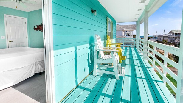 A turquoise room with a bed, a chair, and a view of the ocean. - Coastal Tybee House & Bungalow : Steps from Beach (Tybee Island)