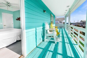 Una habitación turquesa con cama, una silla y vista al océano.