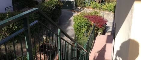 Stroll down the stone staircase to a serene outdoor oasis surrounded by lush greenery and trees.