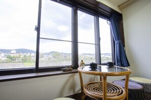 A room with a large window, a table with a clock, and a view of a cityscape. - Kawabata (Kyoto)
