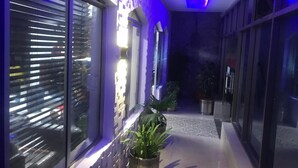 A corridor with a patterned floor, potted plants, and a modern wall with a geometric design. - National City Hotel (Rawalpindi)