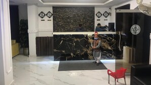A hotel reception area with a marble floor, a reception desk, and a red chair.