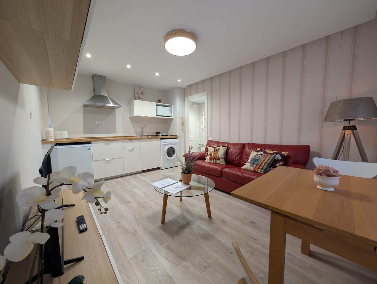 Een modern appartement met een keuken, een eethoek en een woonkamer met een rode bank.