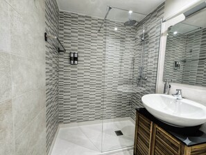A modern bathroom with a glass-enclosed shower, a white sink, and a wooden vanity. - Pidal Apartment - Right in the heart of Oviedo (Oviedo)