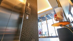 An interior view of a modern elevator with a metallic finish and a textured wall. - HOTEL LiVEMAX AKASAKA (Tokyo)