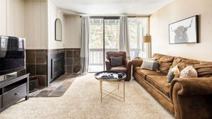 Ein Wohnzimmer mit einem braunen Sofa, einem Couchtisch, einem Fernseher und einem Kamin.