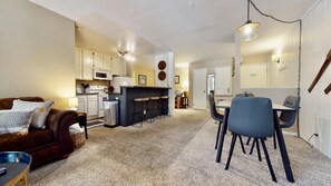 A compact living space with a kitchenette, a dining area, and a seating area with a sofa and chairs.
