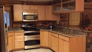 A kitchen with wooden cabinets, a stainless steel microwave, an oven, and a refrigerator.