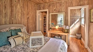 A wooden-paneled room with a bed, bedside table, and a mirror. - Cottage w/ Private Pool - Walk to Lake Wales! (Lake Wales)