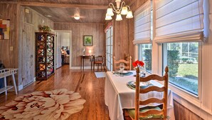 A wooden interior with a dining table set for two, a chandelier, and a view of the outdoors through large windows. - Cottage w/ Private Pool - Walk to Lake Wales! (Lake Wales)