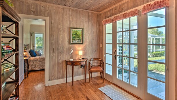A room with wooden walls, a desk with a lamp, a chair, and a bookshelf. - Cottage w/ Private Pool - Walk to Lake Wales! (Lake Wales)