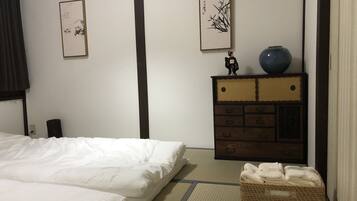 A hotel room with a bed, a dresser, and two wall-mounted paintings.