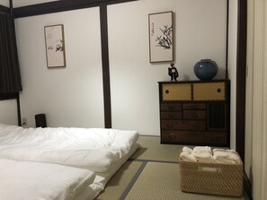Une chambre d’hôtel avec un lit, une commode et deux tableaux accrochés au mur.