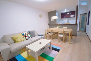 A modern living room with a sofa, coffee table, and dining table.