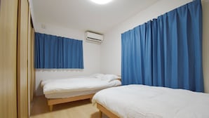 A room with two single beds, a wooden floor, and blue curtains. - Karan Horikawagojo (Kyoto)