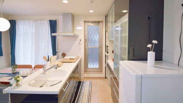 A modern kitchen with a central island, built-in cabinets, and a large window with curtains. - Karan Horikawagojo (Kyoto)