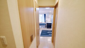 A narrow hallway leading to a room with a bed, a desk, and a window. - Karan Horikawagojo (Kyoto)