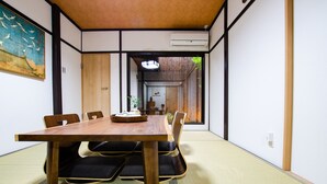 Perinteinen japanilainen huone, jossa on tatamimatto, puinen pöytä ja mustat tyynyt.