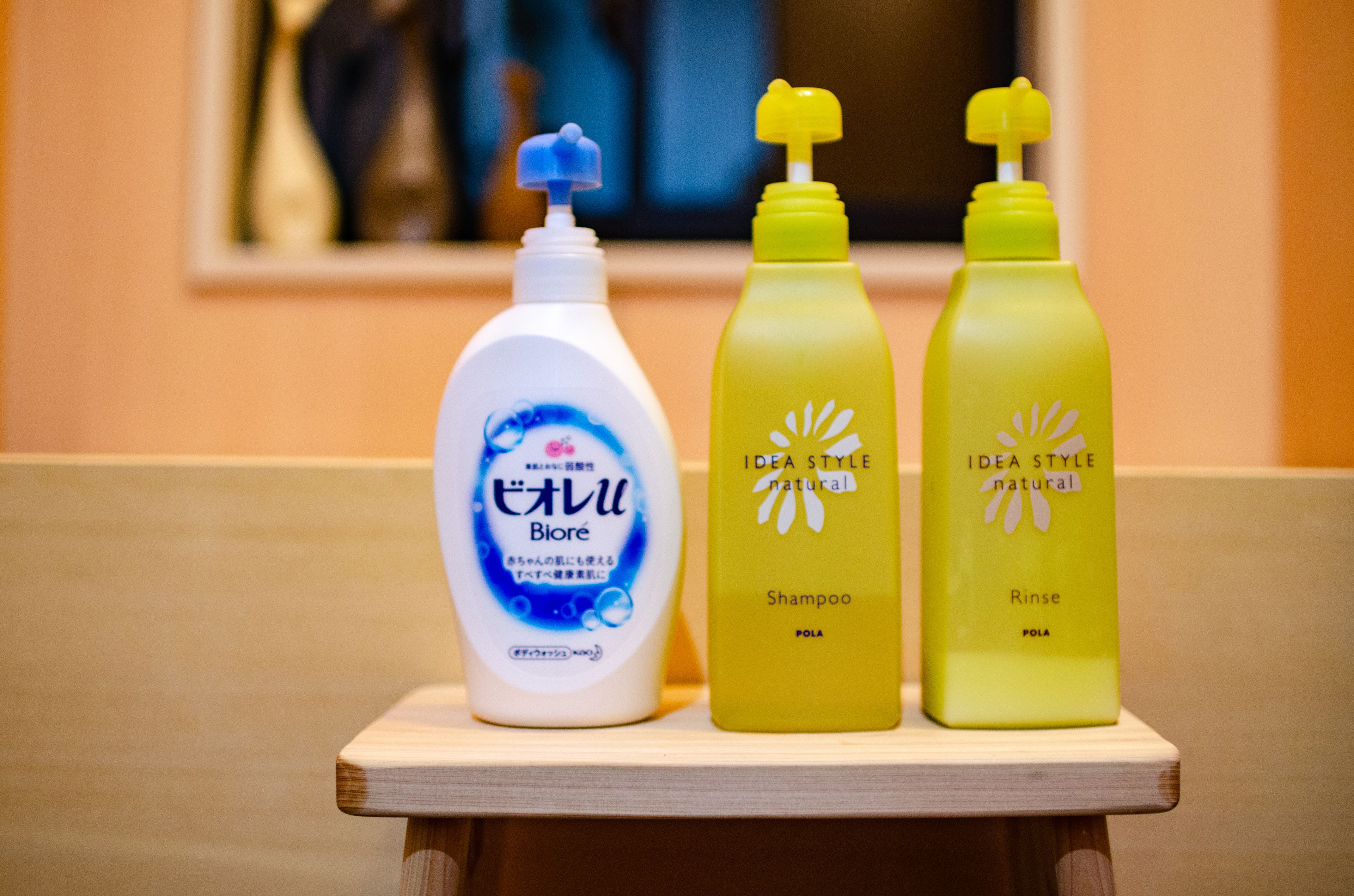 Three bottles of shampoo and rinse on a wooden table.