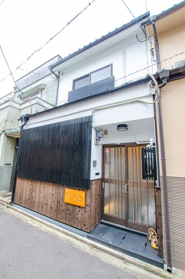A building with a wooden exterior, a metal gate, and a small step leading to the entrance.