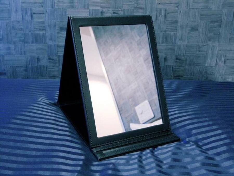 A framed picture on a bed with a blue and white striped bedspread.