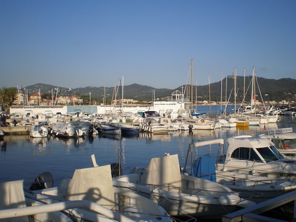 Uma marina com vários barcos atracados, um edifício com a placa