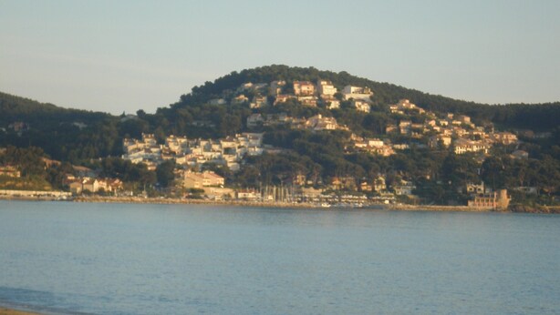A coastal town with buildings on a hillside overlooking a calm sea.