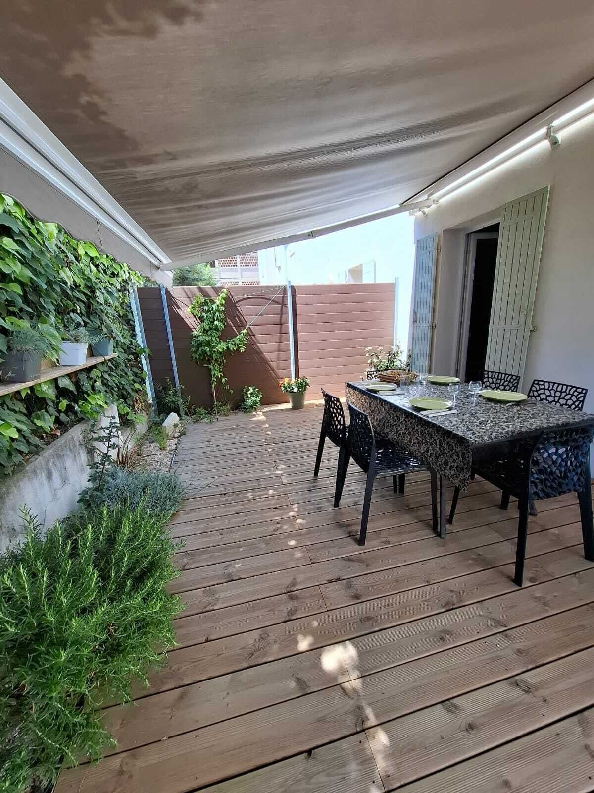 Une terrasse extérieure avec une plateforme en bois, une table dressée pour le repas et un mur recouvert de plantes vertes.