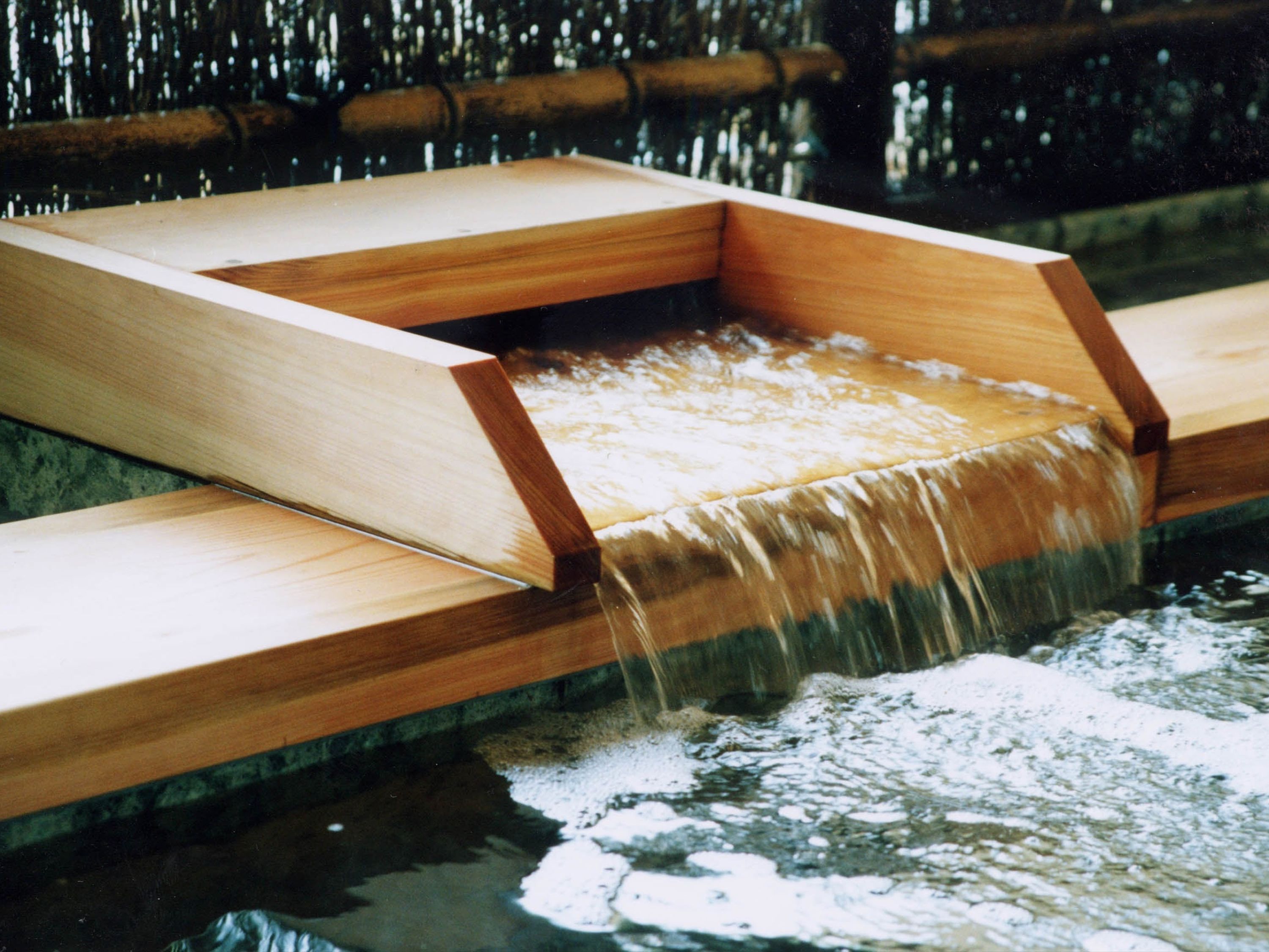 Una fontana in legno con una vasca rettangolare ed effetto cascata.