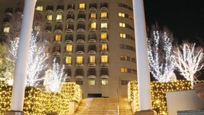 Un edificio con varios pisos, amplias columnas y una escalera que conduce a la entrada.